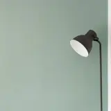Lampada nera su sfondo verde pastello, un'immagine minimalista che evoca tranquillità e semplicità.