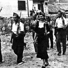Un gruppo di miliziani marcia, tra cui una donna che ricorda Gerda Taro, con fucili in spalla.