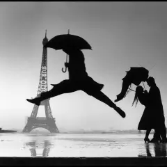 Opera d'arte di Henri Cartier-Bresson: silhouette di un ballerino con ombrello salta davanti alla Torre Eiffel, mentre una coppia si abbraccia sotto un altro ombrello.