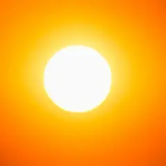 Una foto al sole, con un bagliore intenso che illumina un cielo arancione.