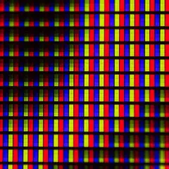 Primo piano di una griglia di pixel RGB. Ogni pixel è composto da sottili barre verticali rosse, verdi e blu, che creano un effetto visivo vibrante, quasi un hot pixel.