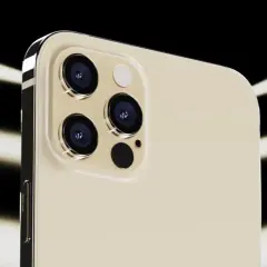 Dettaglio del modulo fotocamera dell'iPhone 12 Pro color oro, con tre obiettivi e flash, illuminato da fasci di luce su sfondo nero.