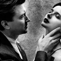 Intenso primo piano di un uomo e una donna, un'iconica scena dei ritratti Helmut Newton, con lui che le sfiora il collo.