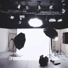 Studio fotografico pronto per uno scatto, con luci, fondale bianco e un potente flash pronto a illuminare la scena.