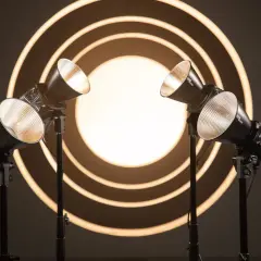 Due luci da studio creano un gioco di luce e ombra su uno sfondo con cerchi concentrici luminosi.