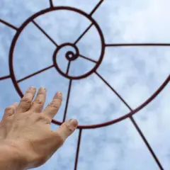 Mano tesa verso il cielo, seguendo la spirale che ricorda la zona aurea.