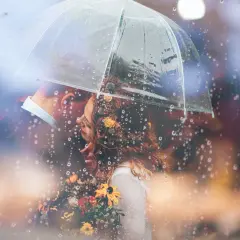 Coppia sotto un ombrello trasparente, con gocce di pioggia che creano un'atmosfera romantica. Una foto con la pioggia che cattura un momento intimo.