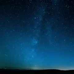 Cielo stellato blu intenso, con la Via Lattea visibile. Un'impresa di fotografare di notte a mano libera, con un leggero bagliore all'orizzonte.