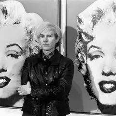 Andy Warhol posa tra i suoi iconici ritratti di Marilyn Monroe, un'immagine che definisce la Pop Art.