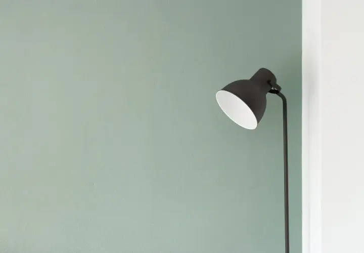 Lampada nera su sfondo verde pastello, un'immagine minimalista che evoca tranquillità e semplicità.