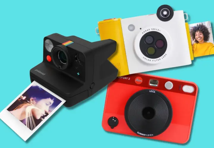 Tre moderne ai fotocamera: una Polaroid nera, una Kodak bianca e gialla, e una Leica rossa.