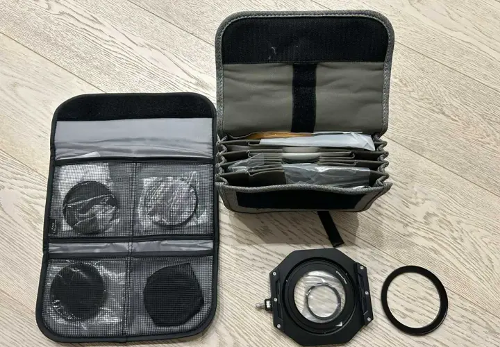 Custodia aperta con vari filtri fotografici rotondi e quadrati, un porta filtro e un anello adattatore.