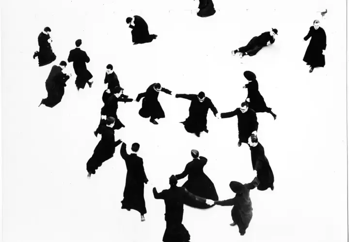 Mario Giacomelli: pretini in cerchio, alcuni in ginocchio, altri in piedi, in un gioco di ombre e forme.