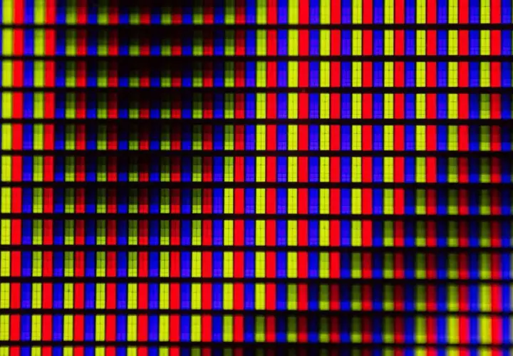 Primo piano di una griglia di pixel RGB. Ogni pixel è composto da sottili barre verticali rosse, verdi e blu, che creano un effetto visivo vibrante, quasi un hot pixel.