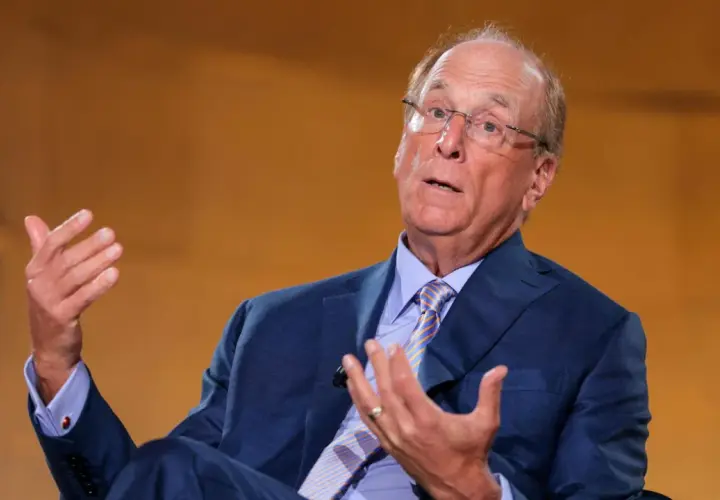 Larry Fink, il fotografo, parla con le mani. Indossa un abito blu e una cravatta a righe.