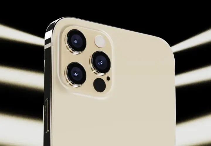 Dettaglio del modulo fotocamera dell'iPhone 12 Pro color oro, con tre obiettivi e flash, illuminato da fasci di luce su sfondo nero.