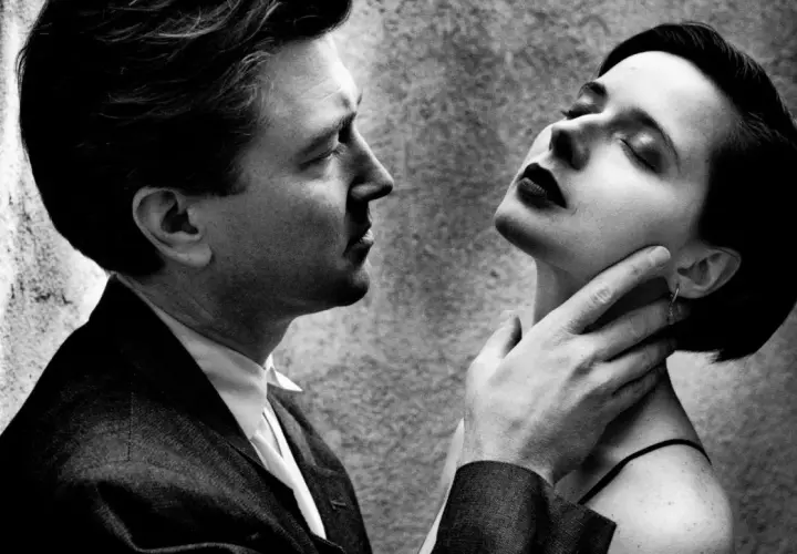 Intenso primo piano di un uomo e una donna, un'iconica scena dei ritratti Helmut Newton, con lui che le sfiora il collo.
