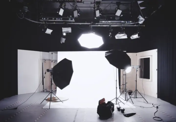 Studio fotografico pronto per uno scatto, con luci, fondale bianco e un potente flash pronto a illuminare la scena.