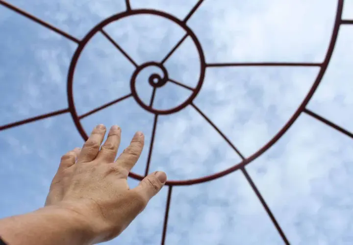 Mano tesa verso il cielo, seguendo la spirale che ricorda la zona aurea.