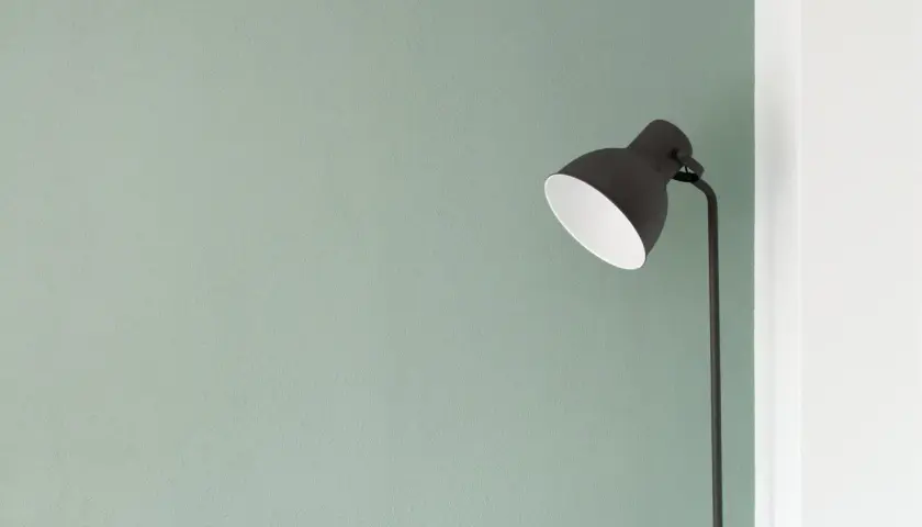 Lampada nera su sfondo verde pastello, un'immagine minimalista che evoca tranquillità e semplicità.