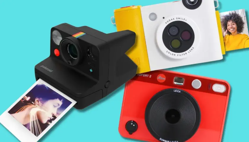 Tre moderne ai fotocamera: una Polaroid nera, una Kodak bianca e gialla, e una Leica rossa.