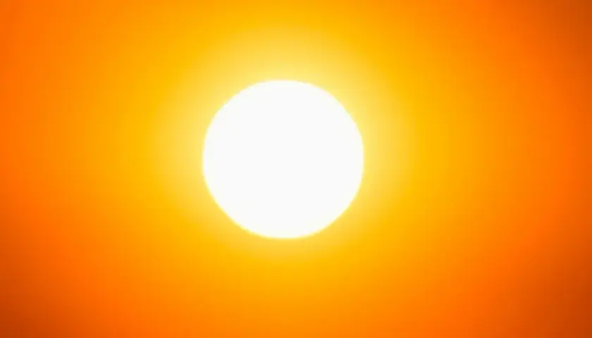Una foto al sole, con un bagliore intenso che illumina un cielo arancione.
