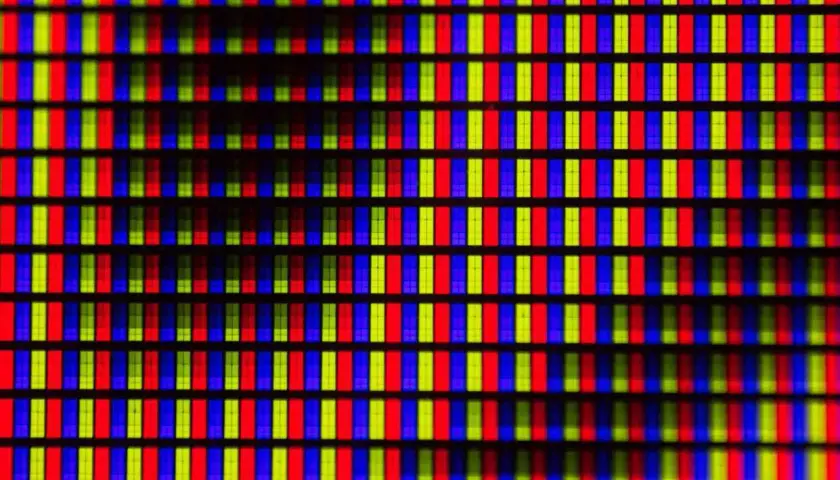 Primo piano di una griglia di pixel RGB. Ogni pixel è composto da sottili barre verticali rosse, verdi e blu, che creano un effetto visivo vibrante, quasi un hot pixel.