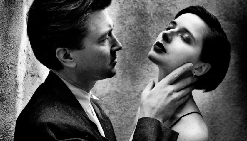 Intenso primo piano di un uomo e una donna, un'iconica scena dei ritratti Helmut Newton, con lui che le sfiora il collo.