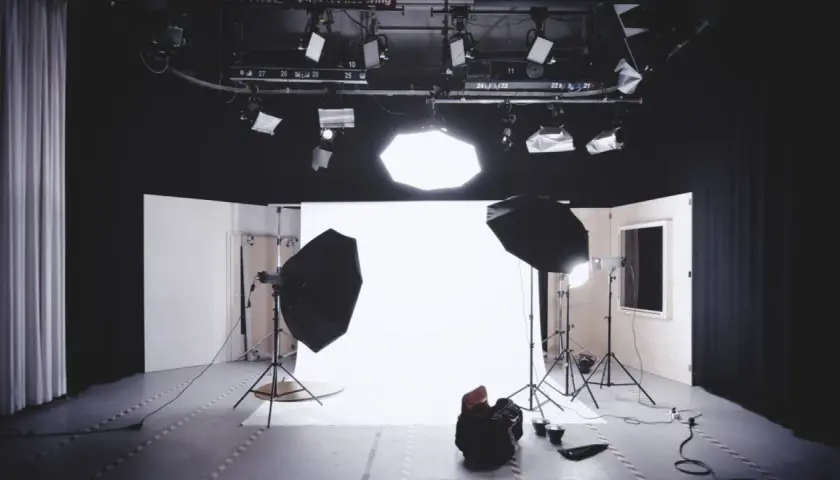 Studio fotografico pronto per uno scatto, con luci, fondale bianco e un potente flash pronto a illuminare la scena.