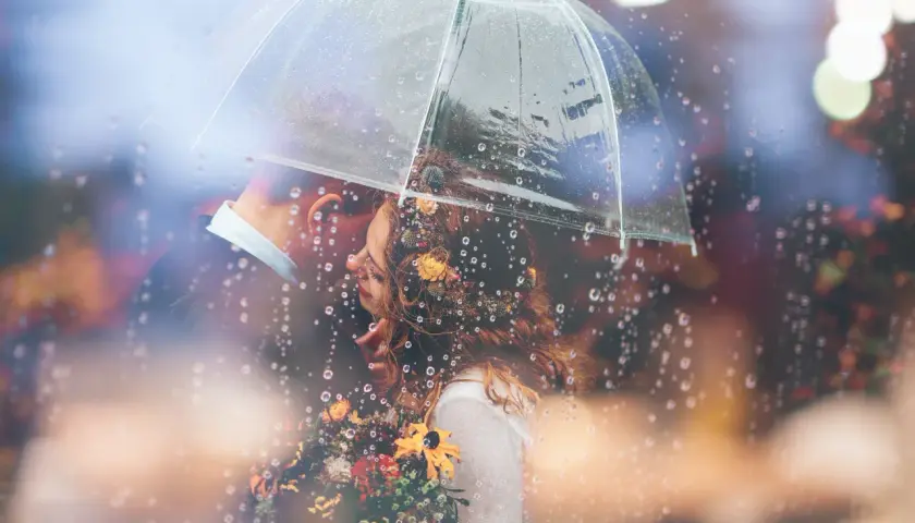 Coppia sotto un ombrello trasparente, con gocce di pioggia che creano un'atmosfera romantica. Una foto con la pioggia che cattura un momento intimo.