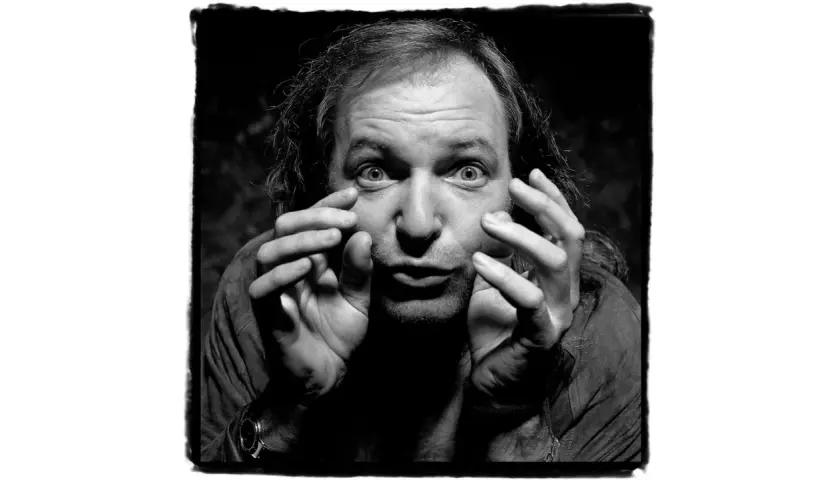 Un uomo con capelli lunghi e occhi spalancati, mani che si muovono vicino al viso. Un'espressione intensa in questa guido harari foto.