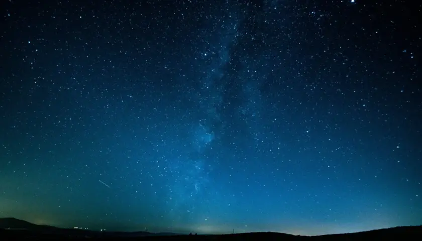 Cielo stellato blu intenso, con la Via Lattea visibile. Un'impresa di fotografare di notte a mano libera, con un leggero bagliore all'orizzonte.