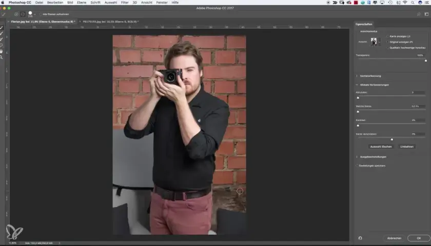 Uomo con fotocamera in mano, sullo sfondo un muro di mattoni. Interfaccia di Photoshop aperta, con pannello "Proprietà" visibile, utile per la selezione rapida Photoshop.