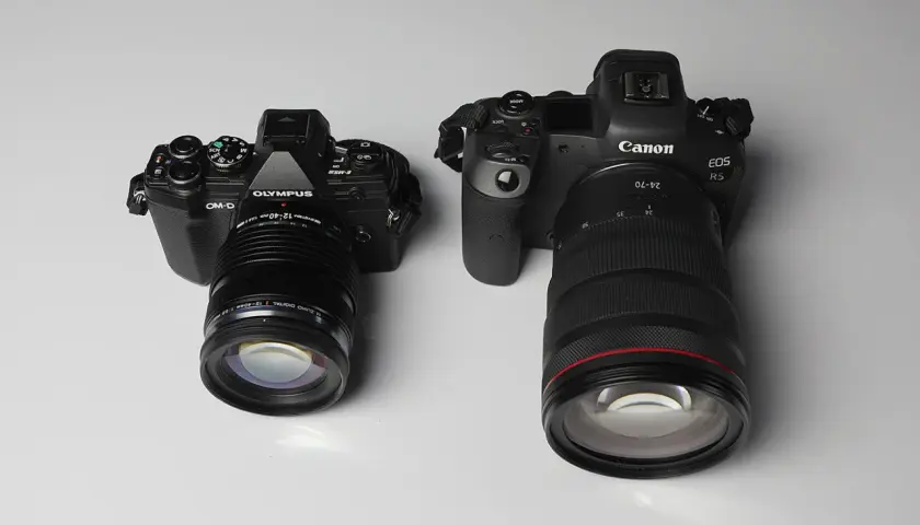 Due fotocamere, una Olympus OM-D in formato micro quattro terzi e una Canon EOS R5, affiancate su sfondo chiaro.