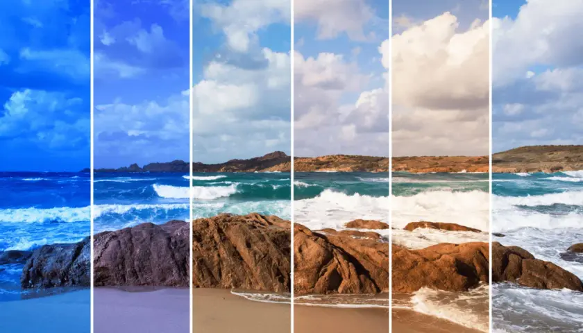 Onde che si infrangono su rocce rosse e sabbia dorata, con un cielo che sfuma dal blu intenso al bianco luminoso.