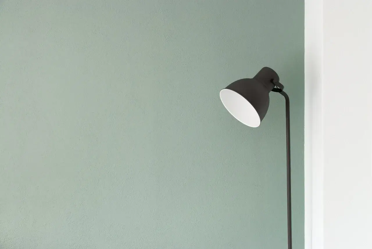 Lampada nera su sfondo verde pastello, un'immagine minimalista che evoca tranquillità e semplicità.