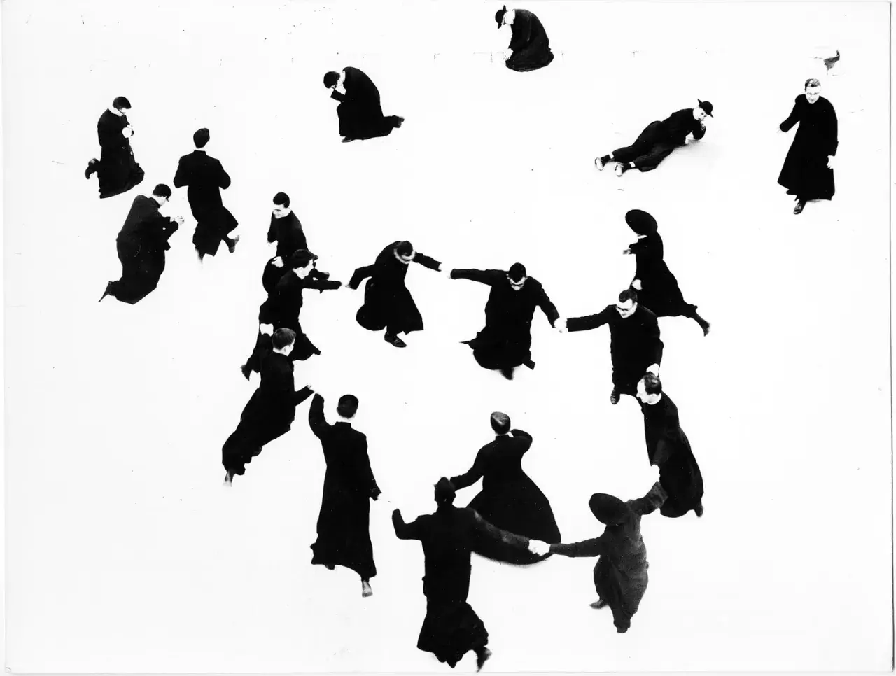 Mario Giacomelli: pretini in cerchio, alcuni in ginocchio, altri in piedi, in un gioco di ombre e forme.