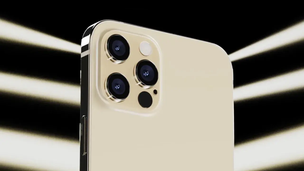 Dettaglio del modulo fotocamera dell'iPhone 12 Pro color oro, con tre obiettivi e flash, illuminato da fasci di luce su sfondo nero.