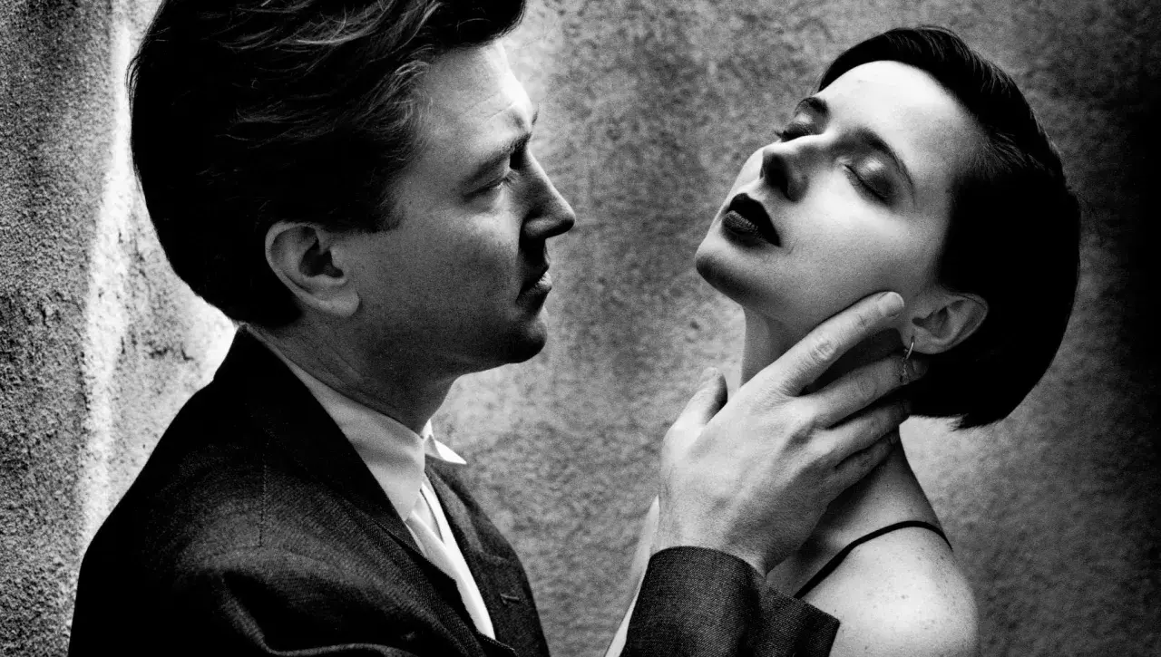 Intenso primo piano di un uomo e una donna, un'iconica scena dei ritratti Helmut Newton, con lui che le sfiora il collo.