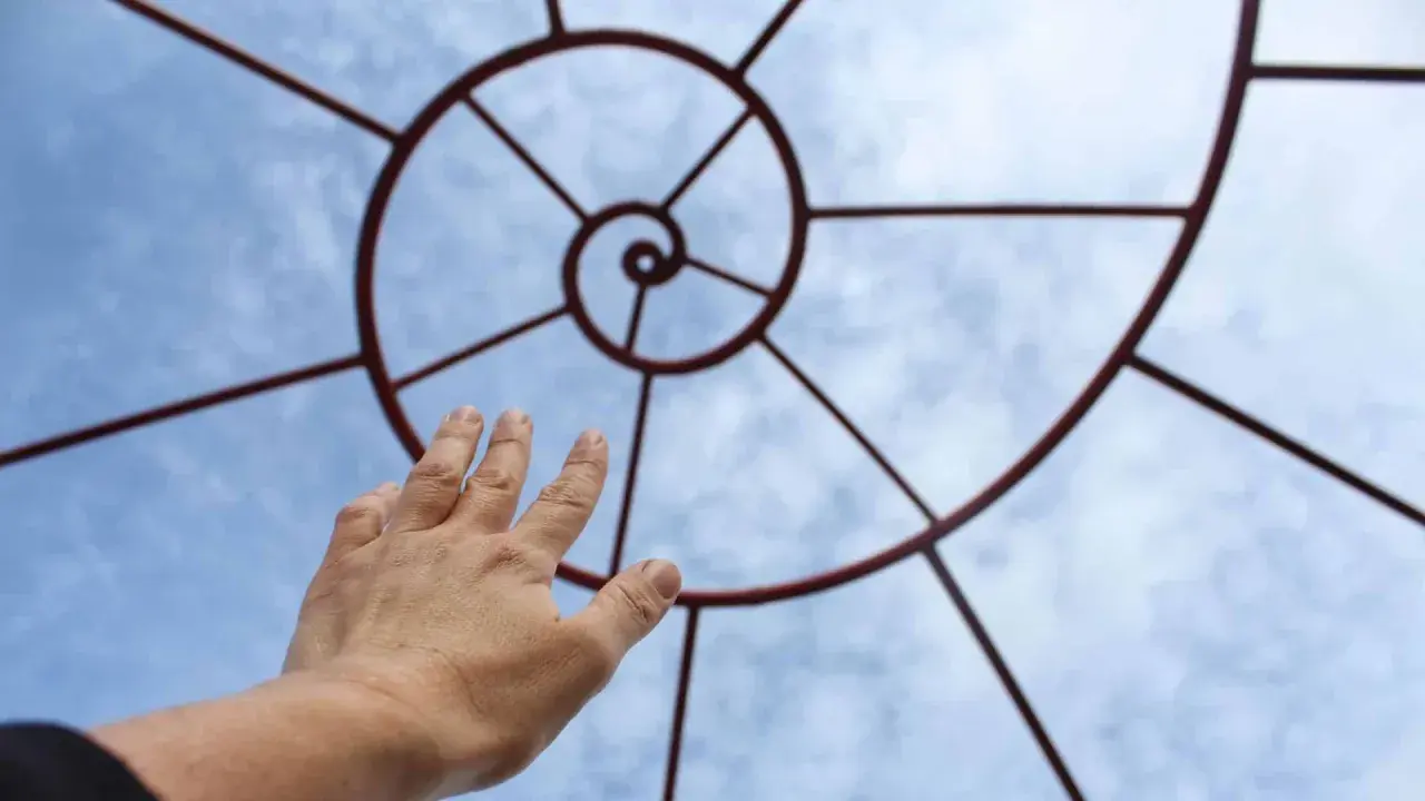 Mano tesa verso il cielo, seguendo la spirale che ricorda la zona aurea.