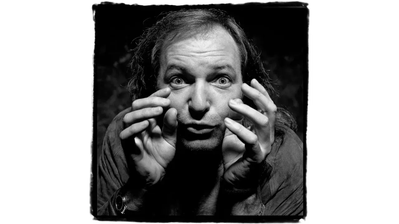 Un uomo con capelli lunghi e occhi spalancati, mani che si muovono vicino al viso. Un'espressione intensa in questa guido harari foto.