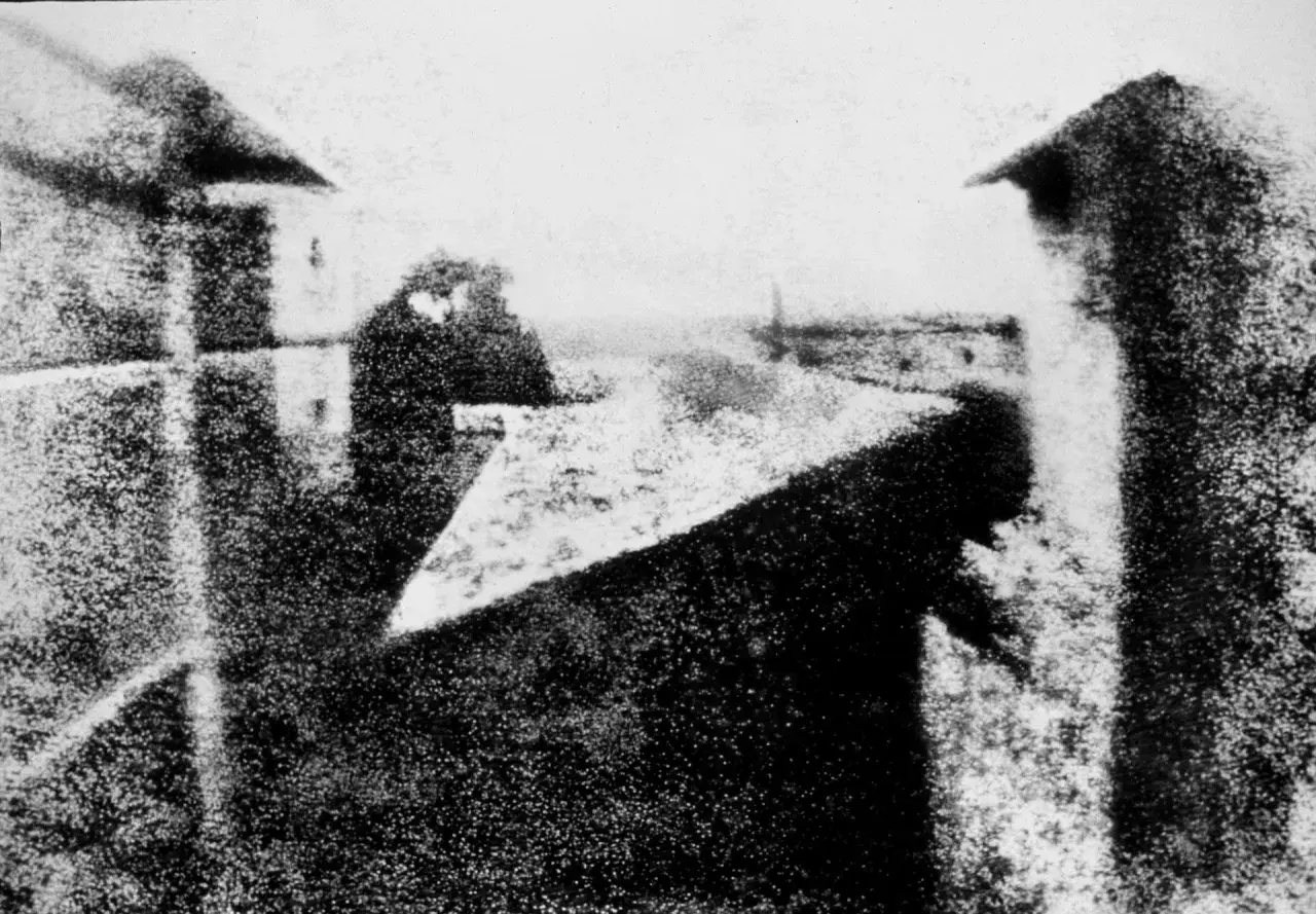 Vista sfocata di edifici e cielo, con una figura indistinta. L'atmosfera ricorda le prime fotografie di Bill Brandt.