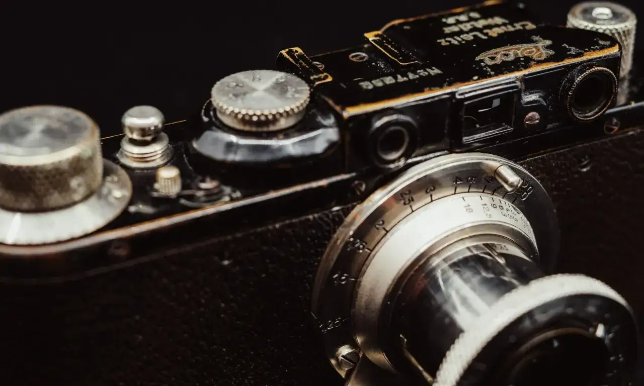 Dettaglio di una fotocamera Leitz Leica vintage, con messa a fuoco sull'obiettivo e sui controlli.