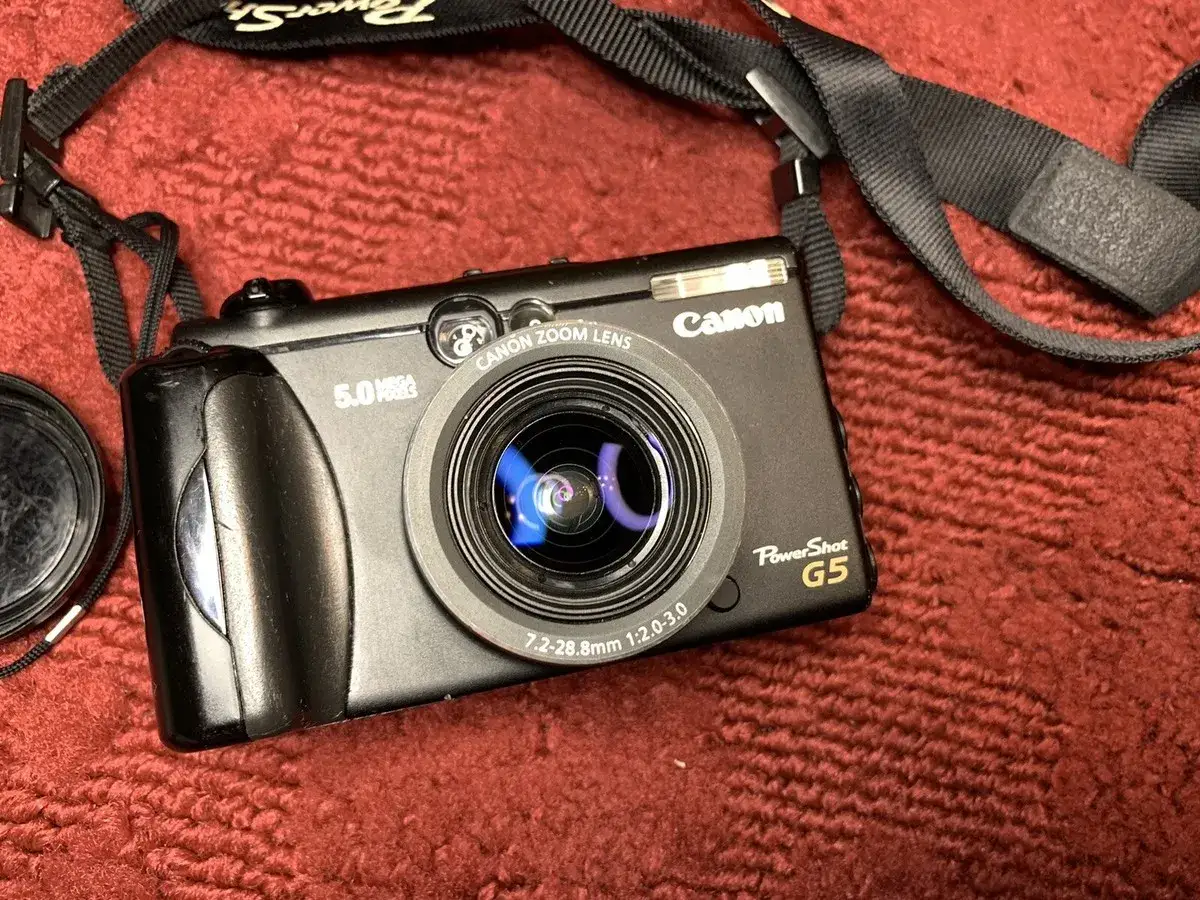 Compatta Canon PowerShot G5 nera, con obiettivo zoom e tracolla, pronta per catturare ricordi.