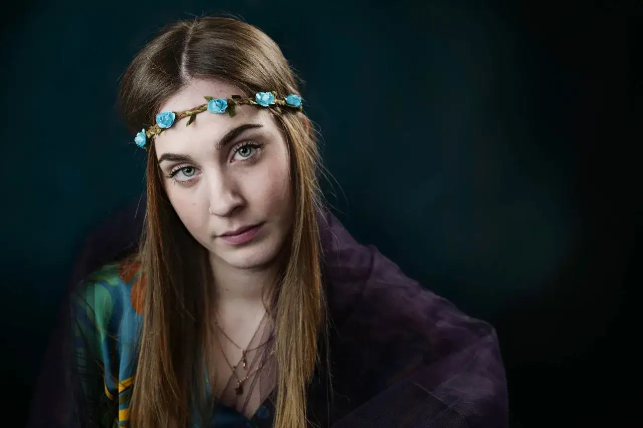Ritratto di giovane donna con coroncina di fiori blu. Impara come usare il flash in manuale per ottenere questo effetto.