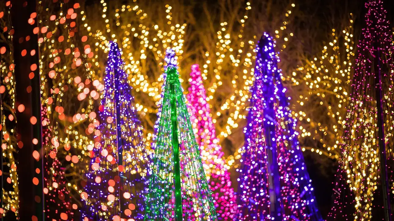 Alberi di Natale stilizzati illuminati da lucine di natale foto, con uno sfondo sfocato di luci dorate e rosse.