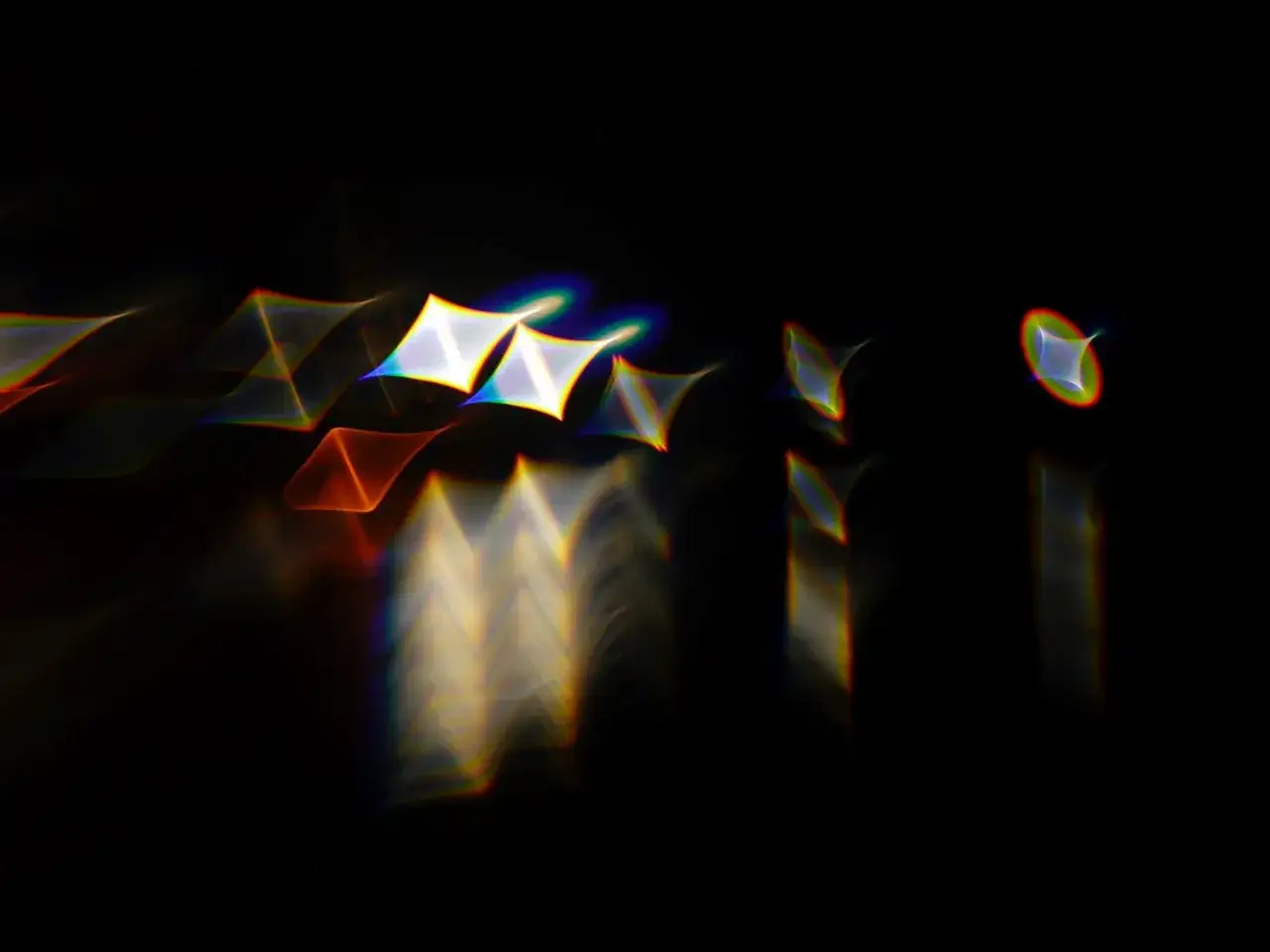 Forme geometriche luminose su sfondo nero, con un effetto di aberrazione cromatica che crea aloni arcobaleno.