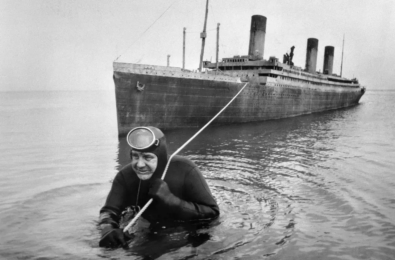 Un subacqueo in muta e maschera si tiene a una corda accanto al Titanic. Foto storiche strane che evocano mistero.