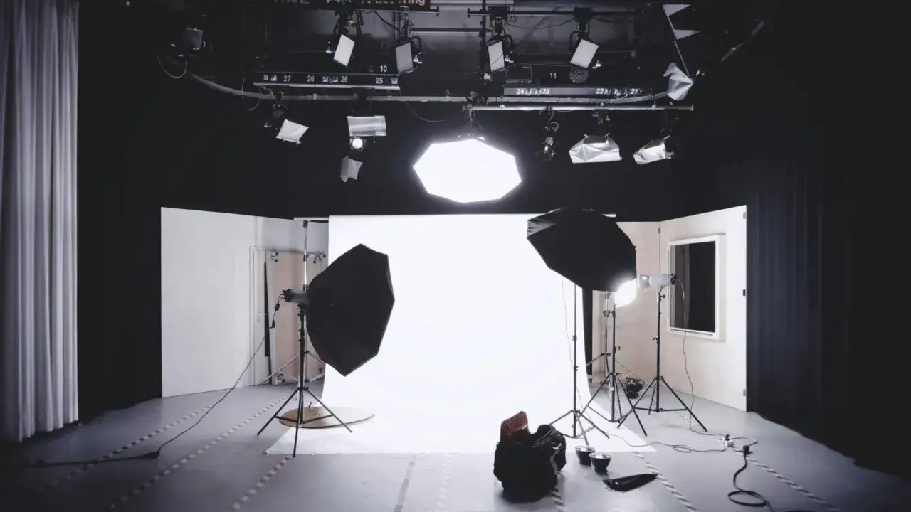 Studio con luci soffuse, fondale bianco e attrezzatura per foto con luce.