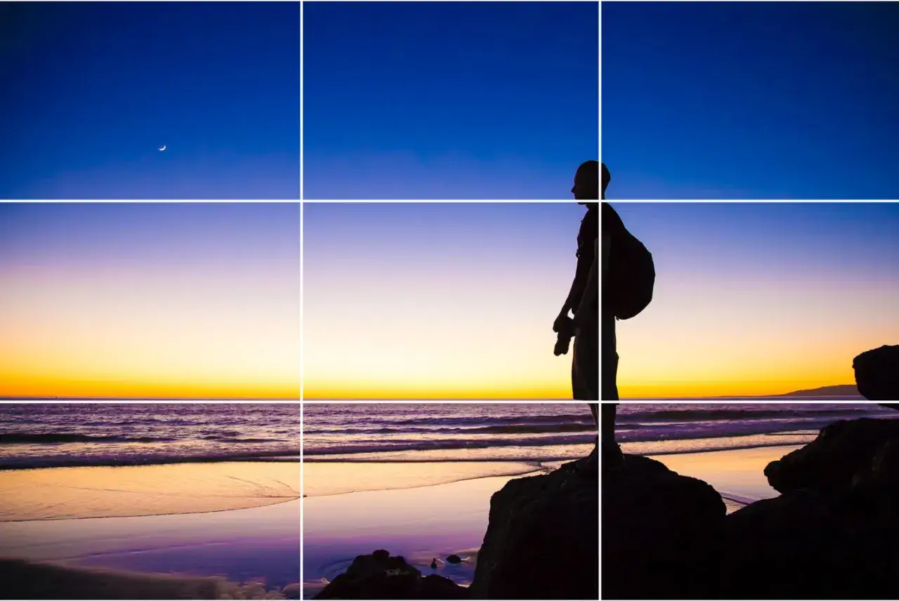 Silhouette di un fotografo al tramonto, con la luna crescente nel cielo. La composizione segue la regola dei terzi, con il soggetto posizionato su un'intersezione.